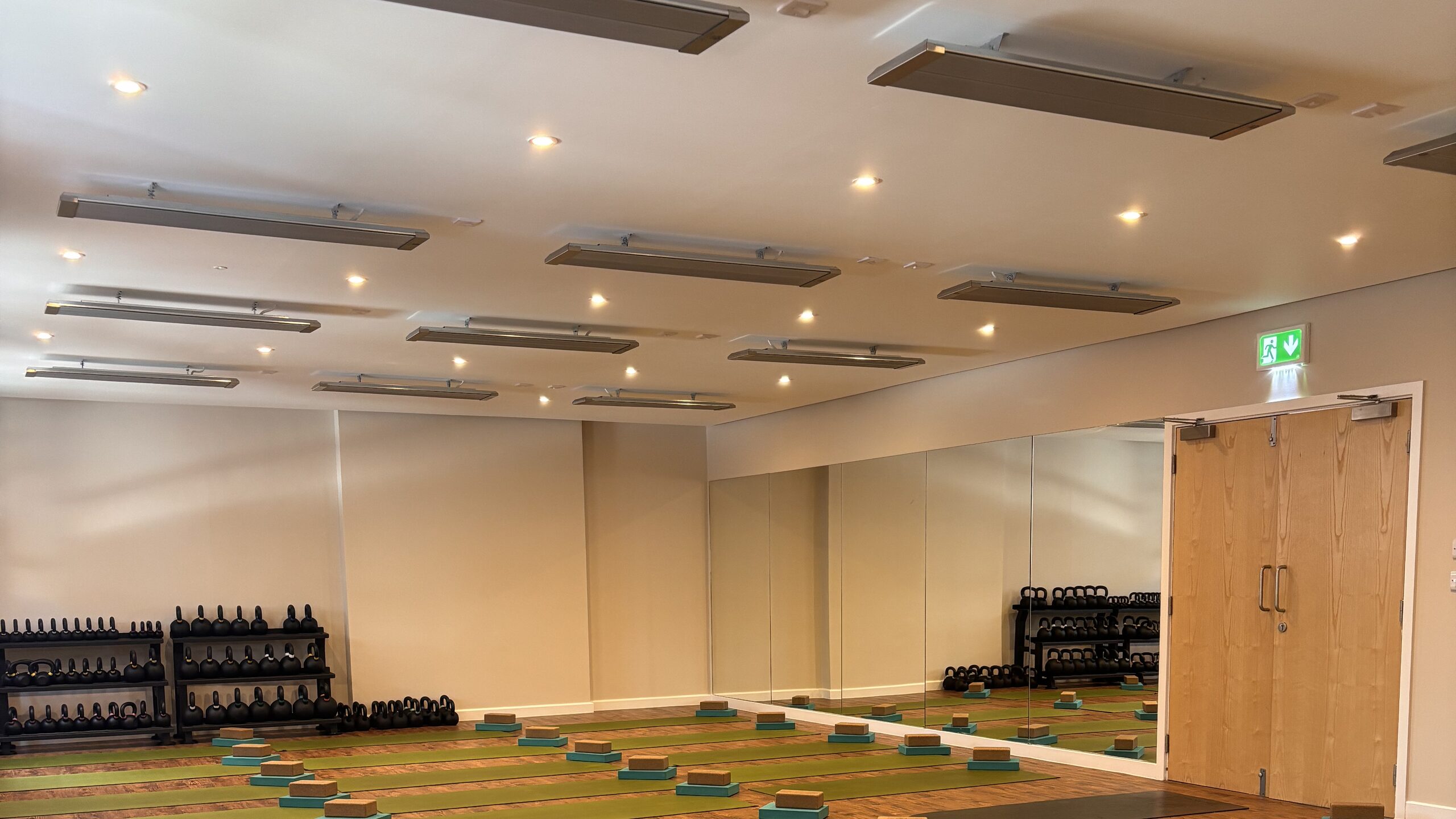 Rows of infrared ceiling heaters in the studio at Deansgate Haus, with mats and blocks laid out below