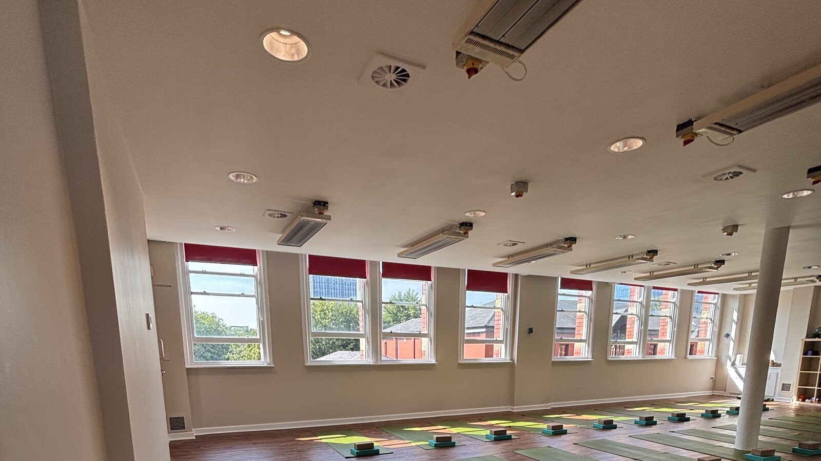 Infrared heaters across the studio ceiling at Deansgate Haus, above a row of tall windows